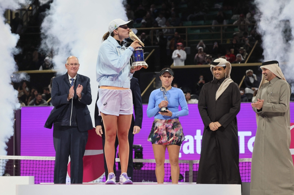 Poland's Iga Swiatek celebrates with the trophy on the podium after defeating US' Jessica Pegula in the final match of the Qatar Open at the Khalifa International Tennis and Squash complex in Doha on February 18, 2023. (Photo by KARIM JAAFAR / AFP)