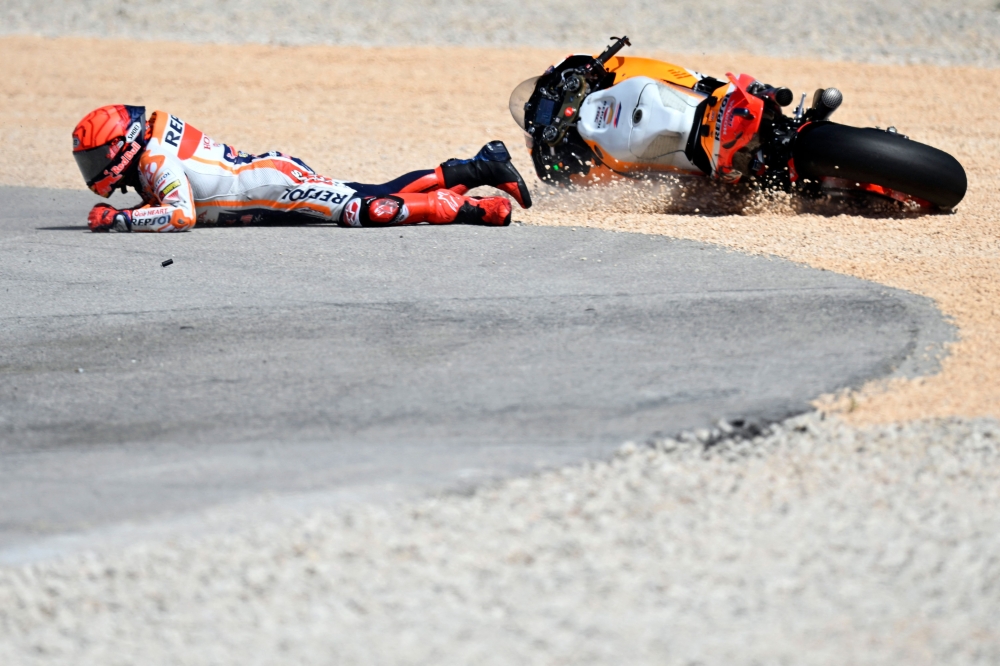 Honda Spanish rider Marc Marquez falls after crashing with Aprilia Portuguese rider Miguel Oliveira (out of frame) during the MotoGP race of the Portuguese Grand Prix at the Algarve International Circuit in Portimao, on March 26, 2023. Photo by PATRICIA DE MELO MOREIRA / AFP