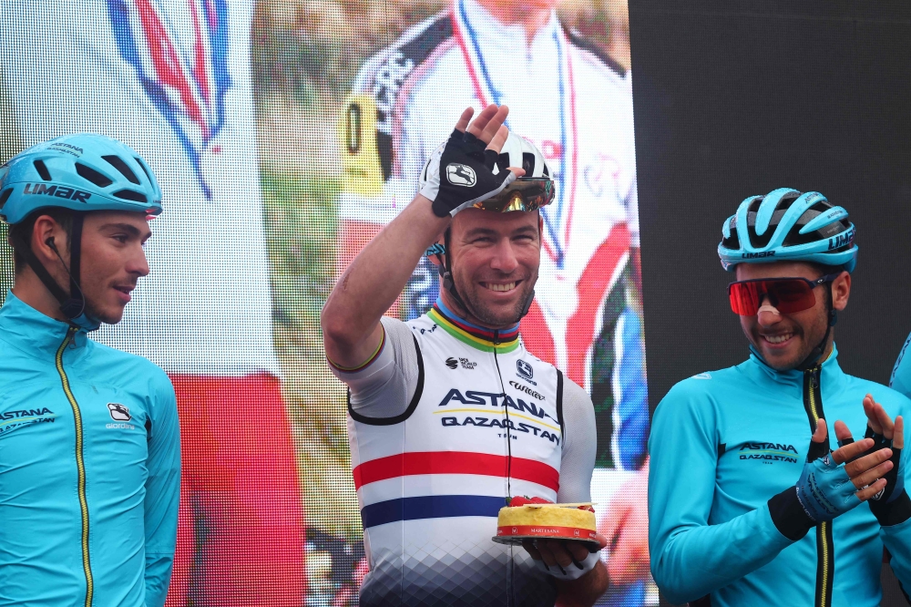 Astana Qazaqstan Team's British rider Mark Cavendish (C), holding a cake to celebrate his 38th birthday, waves during the presentation of the teams prior to the fifteenth stage of the Giro d'Italia 2023 cycling race, 195 km between Seregno and Bergamo, on May 21, 2023. Photo by Luca Bettini / AFP