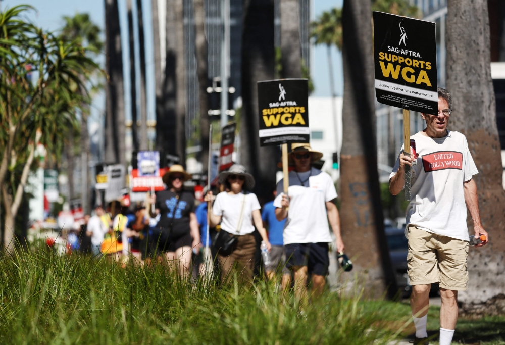 JULY 13: A sign reads 'SAG-AFTRA Supports WGA' as SAG-AFTRA members walk the picket line in solidarity with striking WGA (Writers Guild of America) workers outside Netflix offices on July 13, 2023 in Los Angeles, California. Photo by MARIO TAMA / GETTY IMAGES NORTH AMERICA / Getty Images via AFP