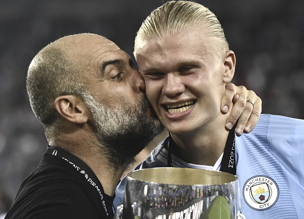 Manchester City's Spanish manager Pep Guardiola (left) kisses Manchester City's Norwegian striker Erling Haaland after winning the 2023 UEFA Super Cup football match between Manchester City and Sevilla at the Georgios Karaiskakis Stadium in Piraeus on August 16, 2023. (Photo by Spyros Bakalis / AFP)