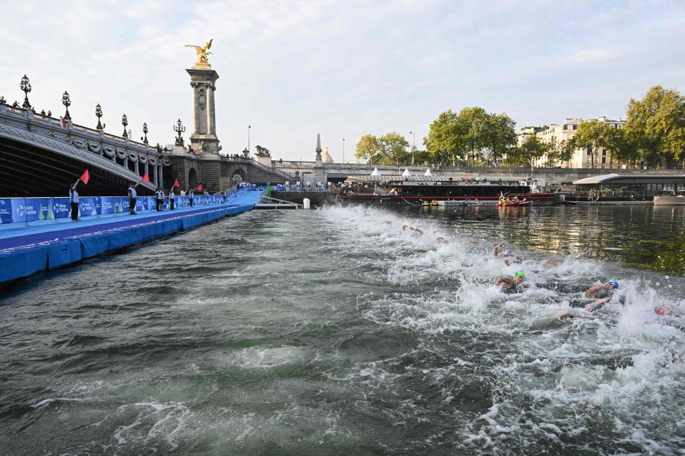 Triathlon athletes swim in The Seine river near the Alexandre III bridge during the men's 2023 World Triathlon Olympic Games Test Event in Paris, on August 18, 2023. Photo by Bertrand GUAY / AFP