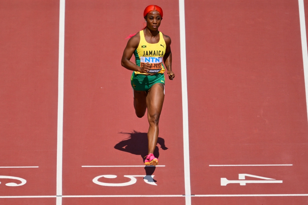 Jamaica's Shelly-Ann Fraser-Pryce crosses the finish line in the women's 100m heats during the World Athletics Championships at the National Athletics Centre in Budapest on August 20, 2023. (Photo by Andrej Isakovic / AFP)