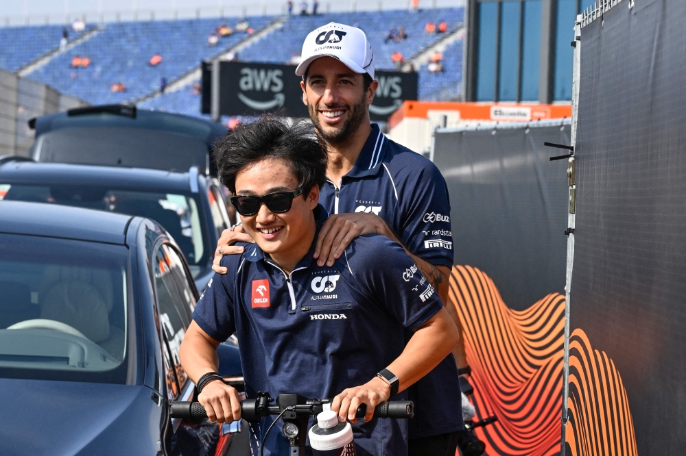 AlphaTauri's Australian driver Daniel Ricciardo (R) arrives on an electric scooter prior to the first practice session at The Circuit Zandvoort, ahead of the Dutch Formula 1 Grand Prix, in Zandvoort on August 25, 2023. (Photo by JOHN THYS / AFP)