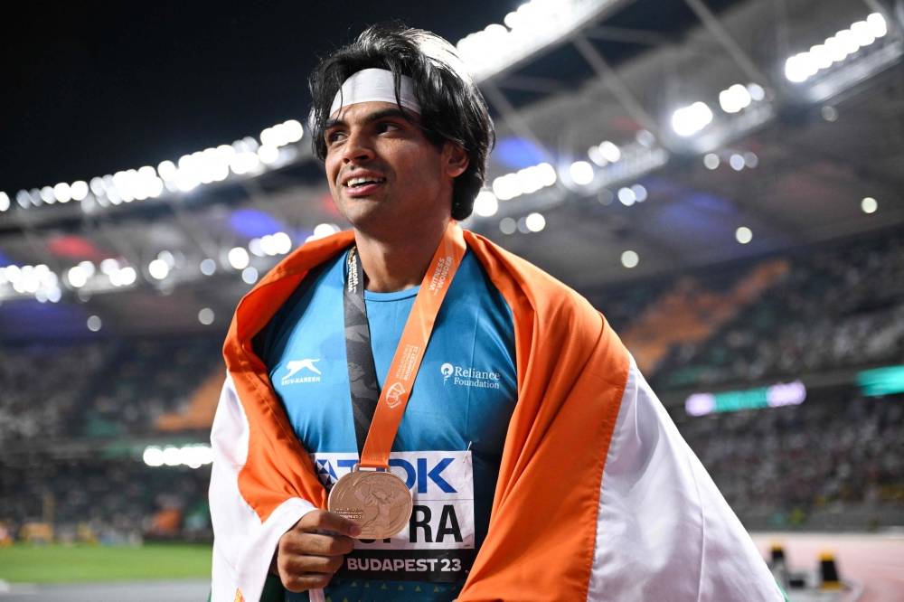 Gold medalist, India's Neeraj Chopra celebrates with his National flag and medal after the men's javelin throw final during the World Athletics Championships at the National Athletics Centre in Budapest on August 27, 2023. (Photo by Kirill Kudryavtsev / AFP)