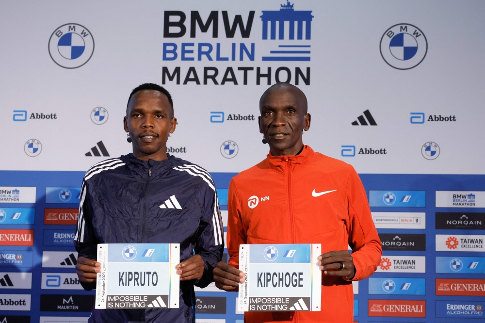 Kenya's world record holder Eliud Kipchoge (R) and Kenya's Amos Kipruto pose with their bib at a press conference on September 22, 2023 in Berlin. (Photo by Odd ANDERSEN / AFP)