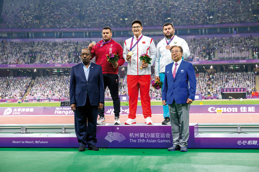 Qatar's Ashraf Amgad Elseify (left) along with China’s Wang Qi (centre) and Uzbekistan’s Sukhrob Khodjaev poses for a picture on the podium. Asian Athletics Association President  Dahlan Al Hamad is also present.  