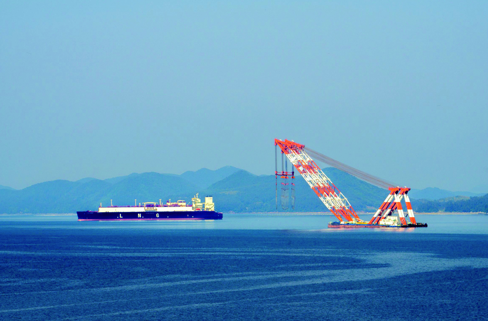 A large liquefied natural gas (LNG) carrier and a floating crane anchor in the harbour near Samsung Heavy Industries in Geoje island, South Korea.