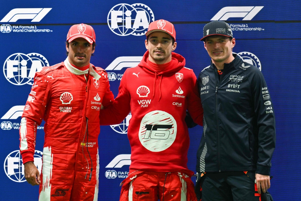 Ferrari's Monegasque driver Charles Leclerc (C) celebrates after finishing in pole position with second place Ferrari's Spanish driver Carlos Sainz Jr. (L) and third place Red Bull Racing's Dutch driver Max Verstappen (R) in Las Vegas, Nevada. (Photo by Angela Weiss / AFP)