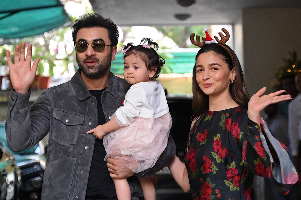 Bollywood actors Ranbir Kapoor (L) and his wife Alia Bhatt pose with their daughter Raha upon their arrival for a Christmas brunch in Mumbai on December 25, 2023. (Photo by Sujit Jaiswal / AFP)
