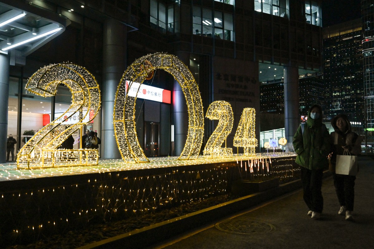 People walk past a light installation for the upcoming new year in Beijing on December 27, 2023. (Photo by JADE GAO / AFP)
