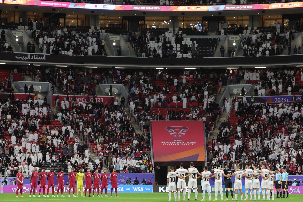 Players observe a moment of silence ahead of the Qatar 2023 AFC Asian Cup football match between Qatar and Palestine at Al-Bayt Stadium in al-Khor, north of Doha, on January 29, 2024. (Photo by Giuseppe CACACE / AFP)
