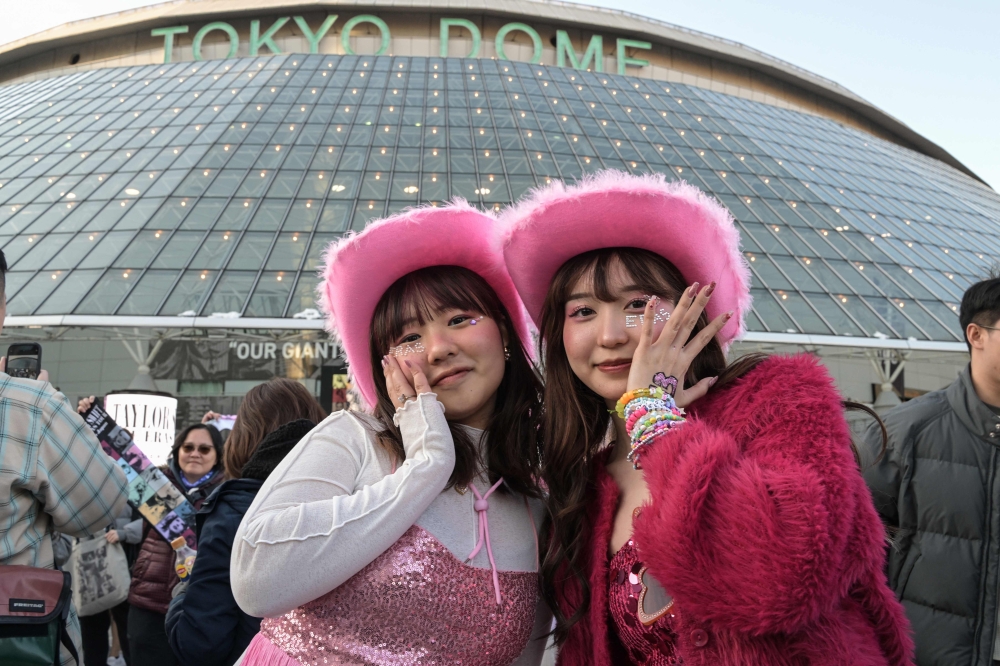 Fans of US singer Taylor Swift, also known as Swifties, pose for photos outside the Tokyo Dome shortly before the start of the first leg of her Asia-Pacific 