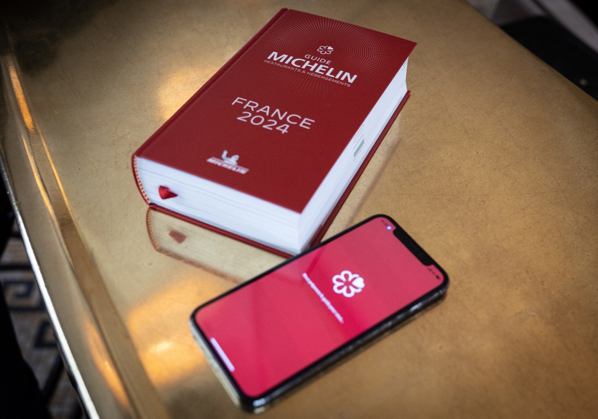 A photograph taken at the Vaudeville brasserie in Paris on March 14, 2024, shows the digital and the printed versions of the 2024 Michelin Guides. Photo by ALAIN JOCARD / AFP