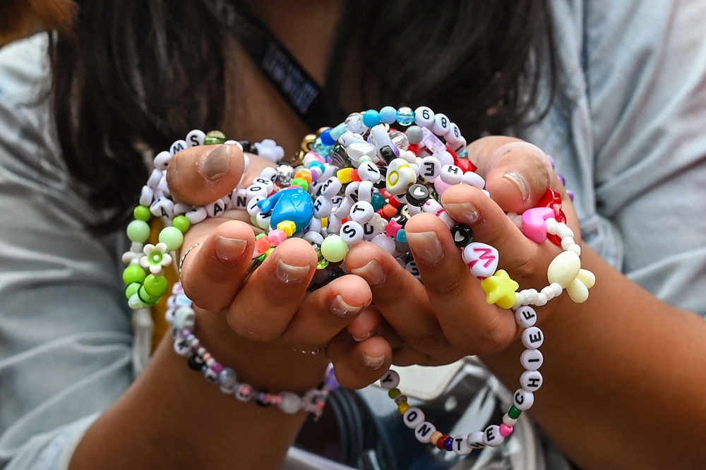 (Files) A fan of US singer Taylor Swift, also known as a Swiftie, holds friendship bracelets as she arrives for the first of the pop star's six sold-out Eras Tour concerts at the National Stadium in Singapore on March 2, 2024. (Photo by Roslan Rahman / AFP)