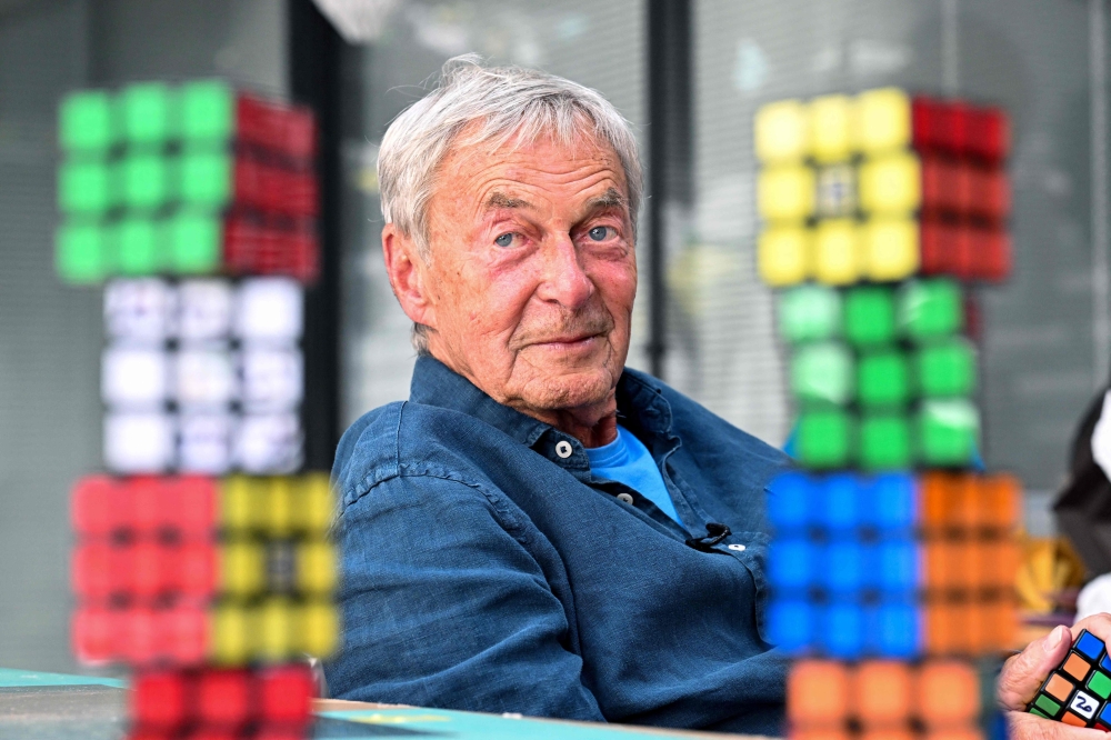 Hungarian inventor Erno Rubik sits next to several Rubik's Cubes during an interview with AFP in Budapest on April 29, 2024. (Photo by Attila Kisbenedek / AFP)