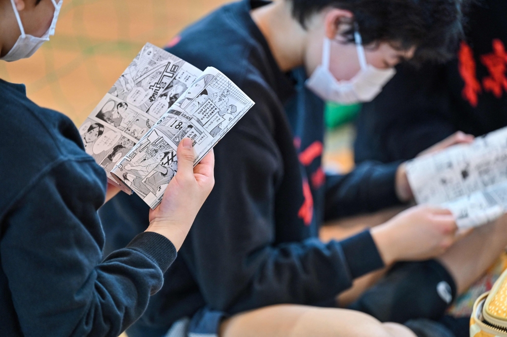 This photo taken on April 13, 2024 shows young players reading the Japanese comic, or manga, 