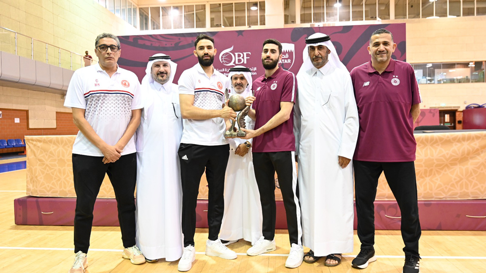 Qatar Basketball Federation Secretary General Saadoun Al Kuwari holds the Amir Cup trophy with the players and officials of Al Sadd and Al Arabi, following a press conference yesterday. 