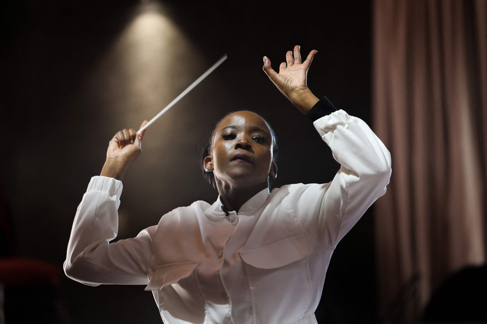 South African conductor Ofentse Pitse waves her conducting baton during rehearsals at Marks Park Sports Club in Johannesburg on June 4, 2024 as they prepare for a show that brings together classical music and popular South African genre, Amapiano. Photo by Phill Magakoe / AFP.