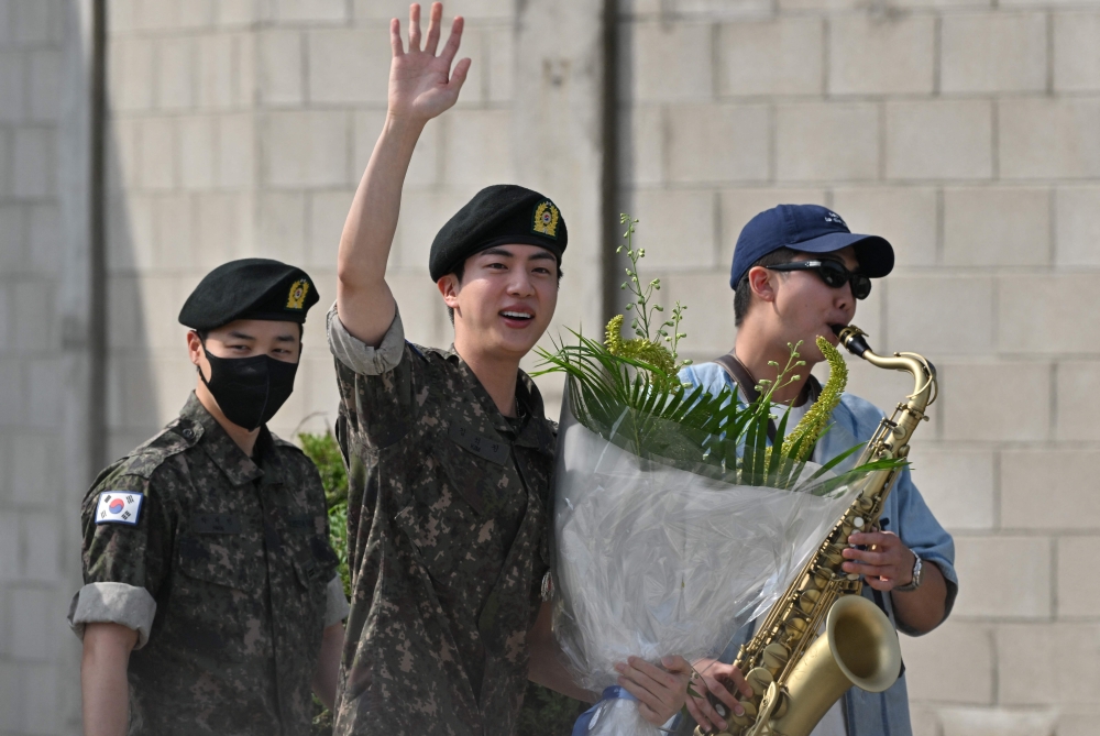 K-pop boy band BTS member Jin (C) waves after being discharged from his mandatory military service next to fellow BTS members RM (R) and Jimin (L) outside a military base in Yeoncheon on June 12, 2024. (Photo by Jung Yeon-je / AFP)