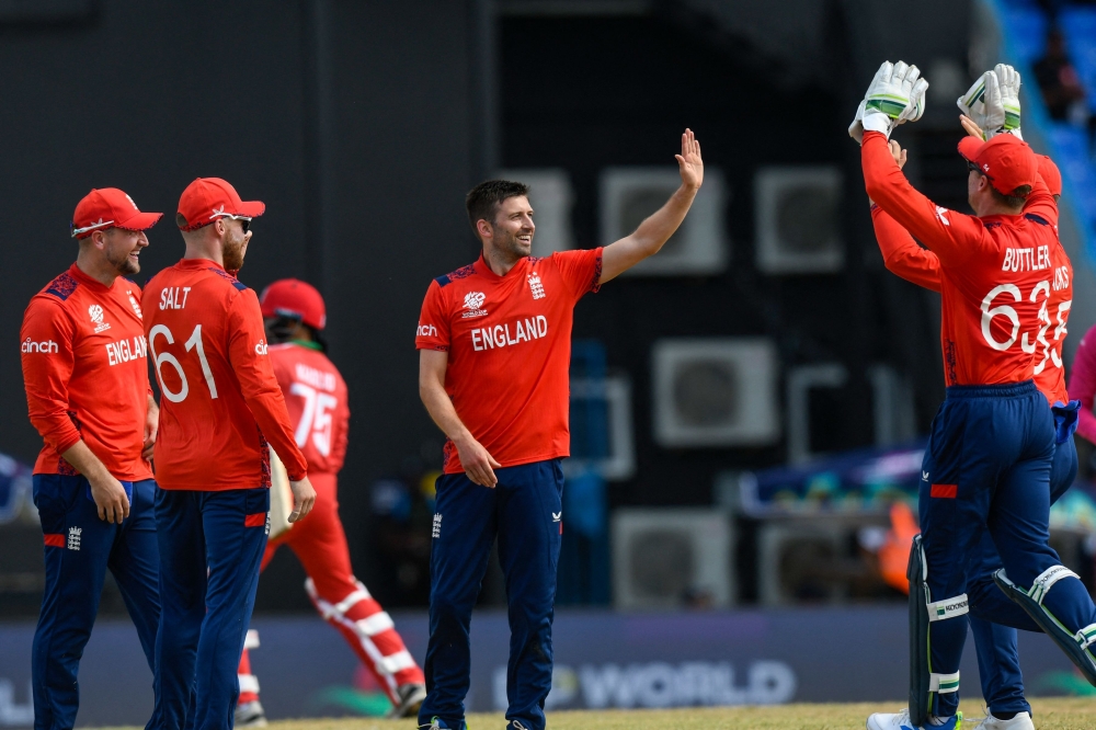 Mark Wood (center) of England celebrates the dismissal of Kashyap Prajapati of Oman during the ICC Men's T20 CWC group B match between England and Oman at Vivian Richards Cricket Stadium in North Sound, Antigua and Barbuda, on June 13, 2024. (Photo by Randy Brooks / AFP)
