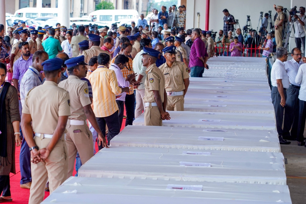 Policemen stand guard as mourning relatives await coffins of the deceased arriving on an Indian Air Force plane from Kuwait at the Cochin International Airport in Kochi on June 14, 2024. (Photo by Arun Chandrabose / AFP)