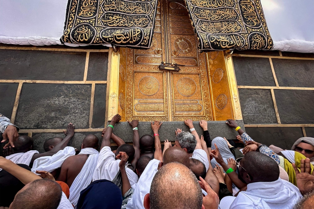 Worshippers pray before and touch the doors of the Kaaba, Islam's holiest shrine, at the Grand Mosque in Saudi Arabia's holy city of Mecca on June 13, 2024. (Photo by Fadel Senna / AFP)