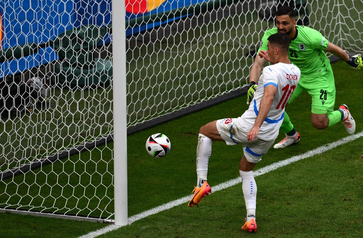 Czech Republic's forward #10 Patrik Schick (L) kicks the ball to score his team's first goal next to Georgia's goalkeeper #25 Giorgi Mamardashvili during the UEFA Euro 2024 Group F football match between Georgia and the Czech Republic at the Volksparkstadion in Hamburg on June 22, 2024. (Photo by Christophe SIMON / AFP)
