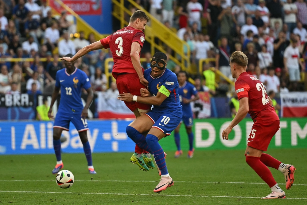 France's forward #10 Kylian Mbappe, wearing a protective mask, fights for the ball with Poland's midfielder #03 Pawel Dawidowicz during the UEFA Euro 2024 Group D football match between France and Poland at the BVB Stadion in Dortmund on June 25, 2024. (Photo by Ozan Kose / AFP)