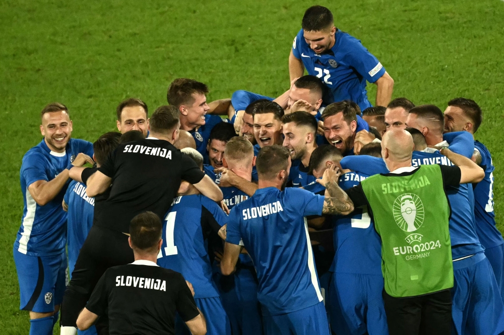 Slovenia's players celebrate qualifying for the knock-out stages on the pitch after the UEFA Euro 2024 Group C football match between England and Slovenia at the Cologne Stadium in Cologne on June 25, 2024. (Photo by Angelos Tzortzinis / AFP)