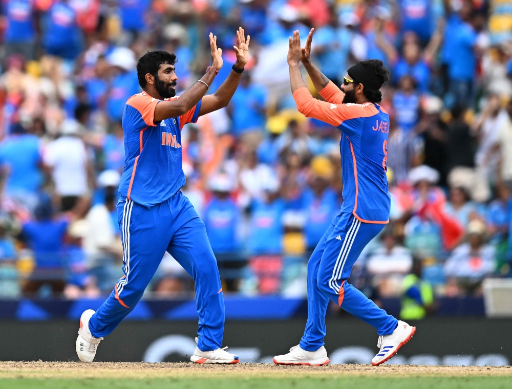 India's Jasprit Bumrah (L) celebrates with India's Ravindra Jadeja after dismissing South Africa's Marco Jansen during the ICC men's Twenty20 World Cup 2024 final cricket match between India and South Africa at Kensington Oval in Bridgetown, Barbados, on June 29, 2024. (Photo by Chandan Khanna / AFP)
