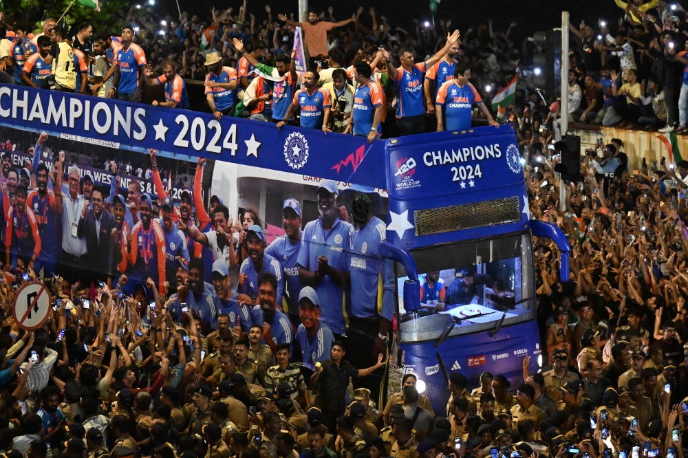 Indian cricketers gesture during an open bus roadshow upon their arrival in Mumbai on July 4, 2024, after winning the ICC men's Twenty20 World Cup in Barbados. (Photo by Punit PARANJPE / AFP)
