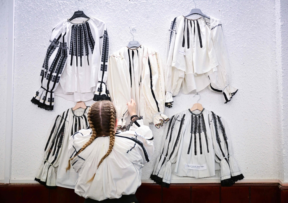 A woman from Sibiu region arranges traditional blouses at an exhibition of traditional Romanian Blouses in Vaideeni village, south-central Romania, on June 29, 2024. (Photo by Daniel Mihailescu / AFP)
