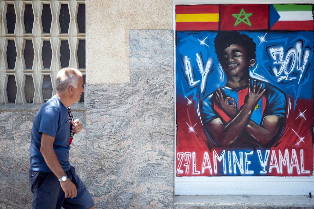 A man walks past a graffiti depicting Lamine Yamal in Rocafonda, the neighbourhood where Spain's forward grew up, in Mataro, 35km from Barcelona, on July 11, 2024. (Photo by Josep Lago / AFP)