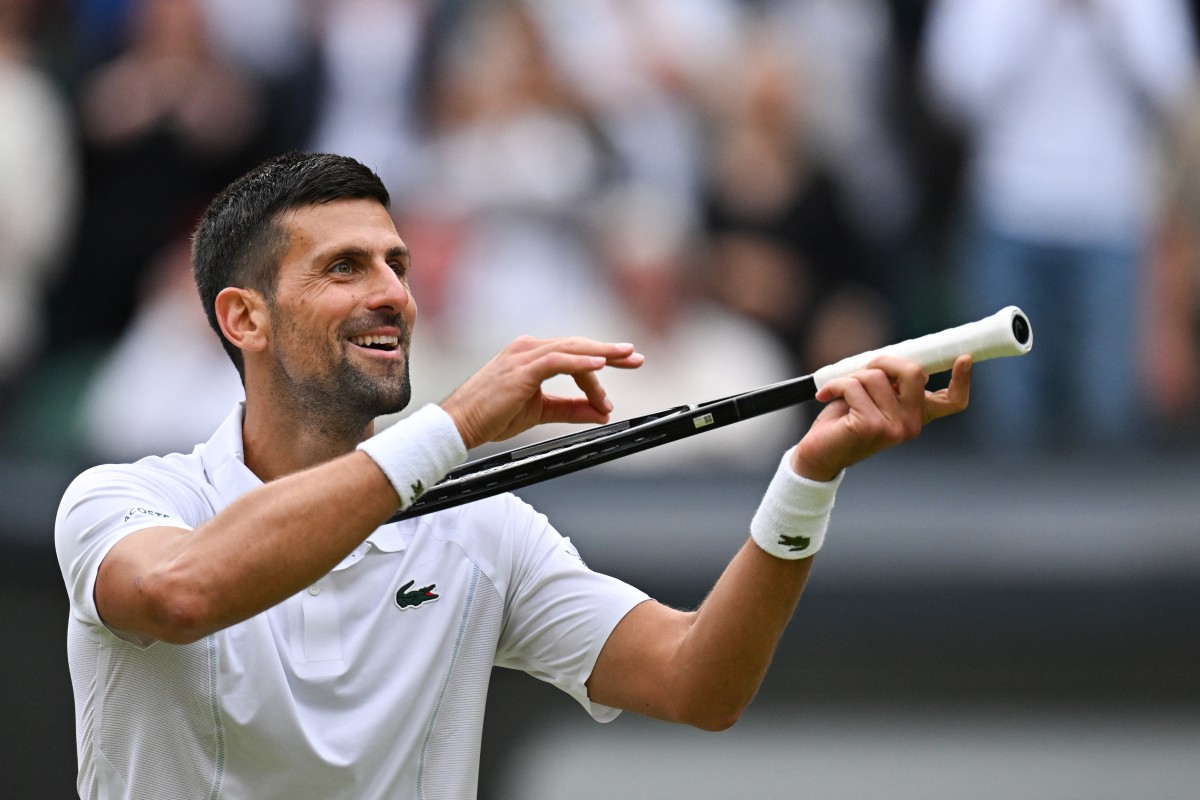 Serbia's Novak Djokovic imitates playing the violin with his racquet as he celebrates winning against Italy's Lorenzo Musetti during their men's singles semi-final tennis match on the twelfth day of the 2024 Wimbledon Championships at The All England Lawn Tennis and Croquet Club in Wimbledon, southwest London, on July 12, 2024. (Photo by ANDREJ ISAKOVIC / AFP) / RESTRICTED TO EDITORIAL USE