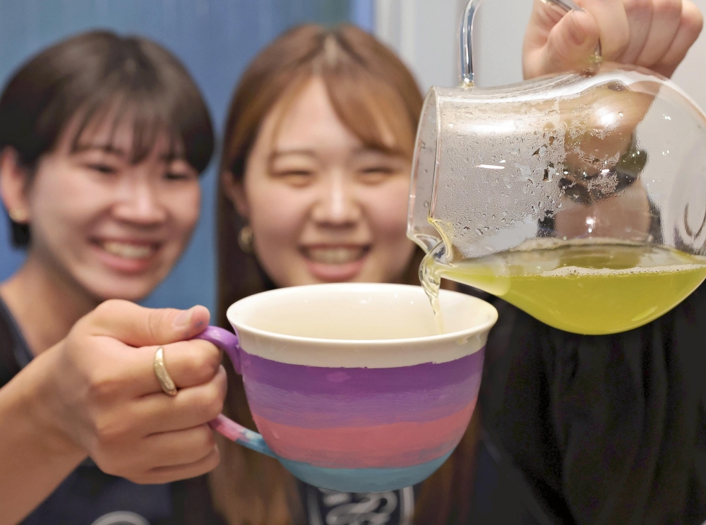 A participant at Edo Saryo (Craft and Cafe) Aoyama pours tea into a cup that has just been painted before enjoying it with a friend. (Photo by Yoshinobu Goto/The Japan News)

