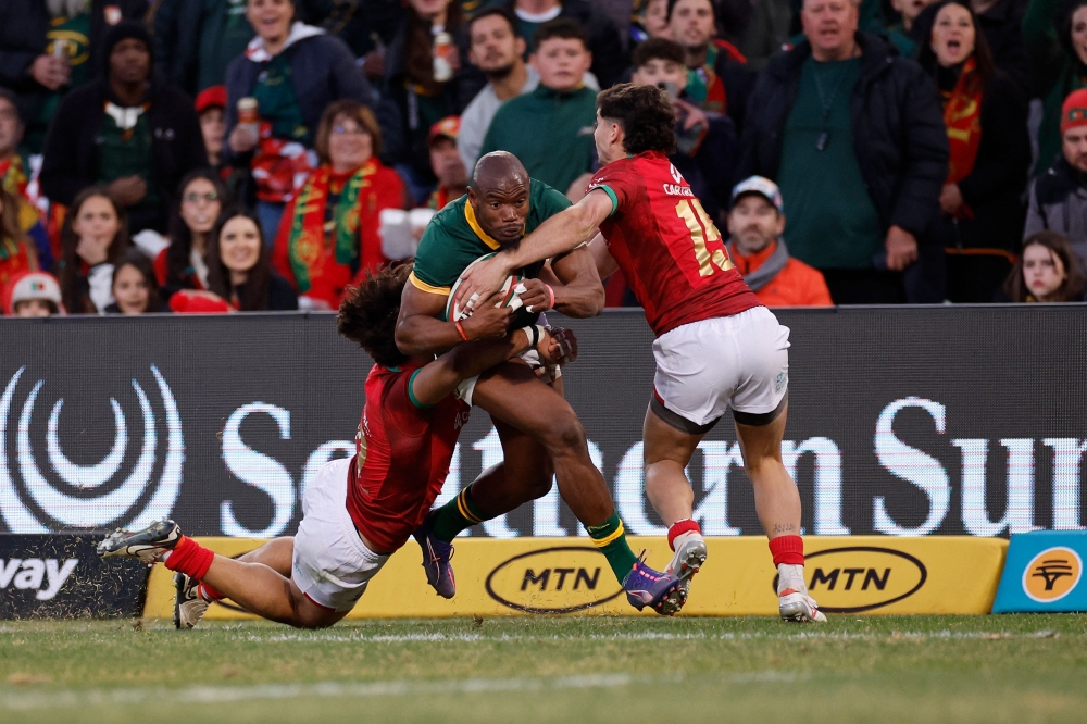 South Africa's wing Makazole Mapimpi (C) is tackled by Portugal's centre Tomas Appleton (L) and Portugal's full-back Simao Bento (R) during the International rugby union match between South Africa and Portugal at the Toyota Stadium in Bloemfontein on July 20, 2024. (Photo by Phill Magakoe / AFP)
