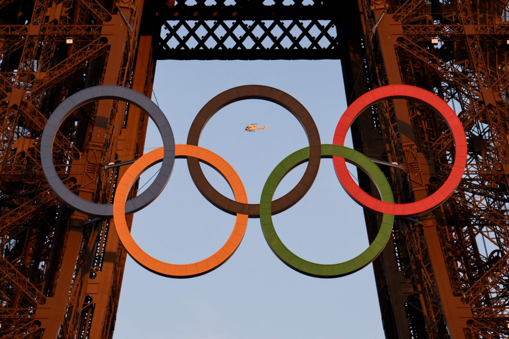 A helicopter flies around the Eiffel Tower with the Olympic rings displayed on it, in Paris on July 21, 2024, ahead of the Paris 2024 Olympic and Paralympic games. (Photo by Luis ROBAYO / AFP)