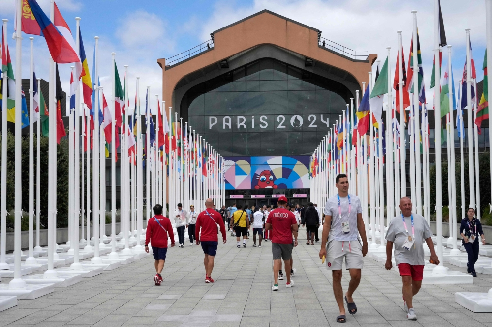 Participants of the Paris 2024 Olympics and Paralympics game walk in front of the cafeteria of the Olympic Village, in Saint-Denis, northern Paris, on July 22, 2024. (Photo by Michel Euler / Pool / AFP)