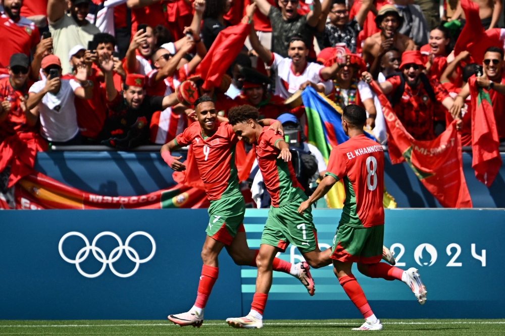 Morocco's forward #09 Soufiane Rahimi (left) celebrates with Morocco's forward #07 Eliesse Ben Seghir (centre) and Morocco's midfielder #08 Bilal El Khannouss after scoring a penalty and his team's second goal in the men's group B football match between Argentina and Morocco during the Paris 2024 Olympic Games at the Geoffroy-Guichard Stadium in Saint-Etienne on July 24, 2024. (Photo by Arnaud Finistre / AFP)