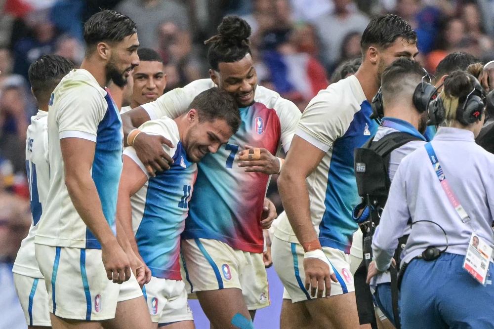 France's Antoine Dupont (C) and teammates celebrate after the men's gold medal rugby sevens match between France and Fiji during the Paris 2024 Olympic Games at the Stade de France in Saint-Denis on July 27, 2024. (Photo by CARL DE SOUZA / AFP)
