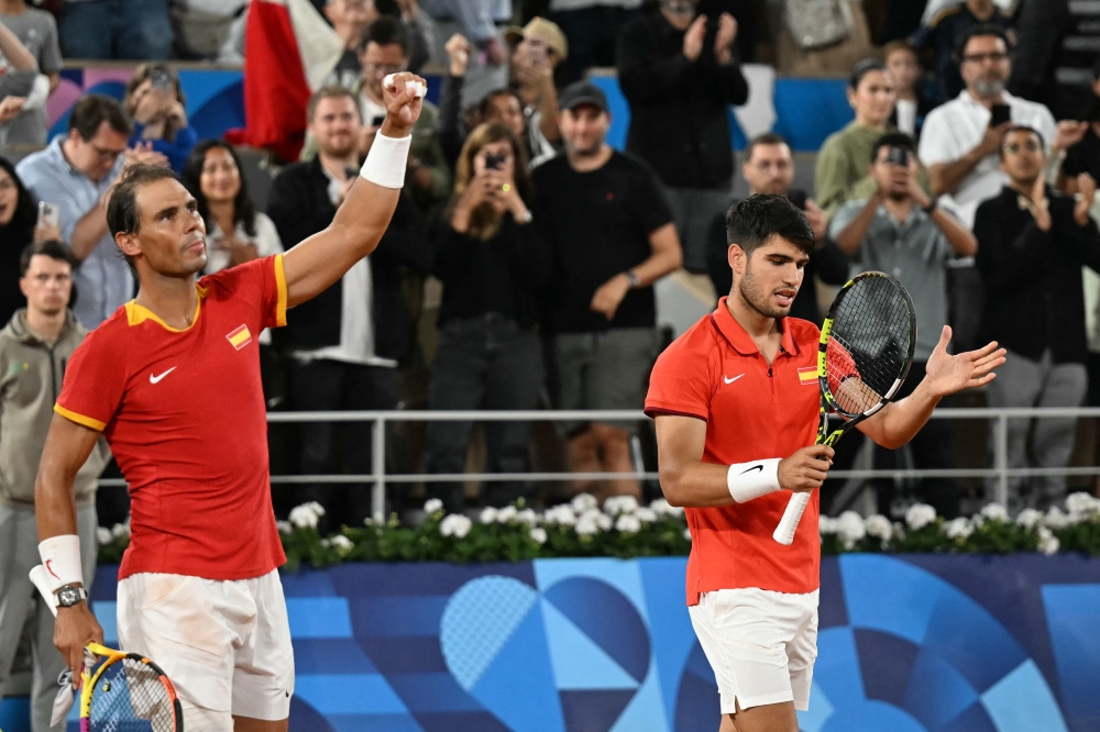 Spain's Rafael Nadal (L) and Spain's Carlos Alcaraz (R) celebrate after beating Argentina's Maximo Gonzalez and Argentina's Andres Molteni in their men's doubles first round tennis match on Court Philippe-Chatrier at the Roland-Garros Stadium at the Paris 2024 Olympic Games, in Paris on July 27, 2024. (Photo by MARTIN BERNETTI / AFP)
