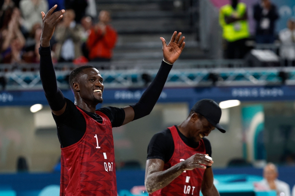 Qatar's #01 Cherif Younousse and Qatar's #02 Ahmed Tijan celebrate a point in the men's pool A beach volleyball match between Italy and Qatar during the Paris 2024 Olympic Games at the Eiffel Tower Stadium in Paris on July 27, 2024. (Photo by Luis TATO / AFP)
