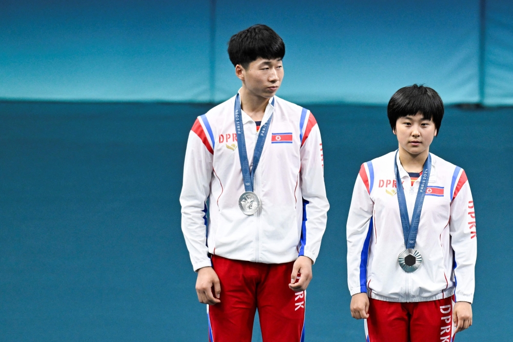 Silver medalists North Korea's Ri Jong Sik (L) and North Korea's Kim Kum Yong celebrate on the podium at the end of their mixed table tennis doubles competition at the Paris 2024 Olympic Games at the South Paris Arena in Paris on July 30, 2024. (Photo by WANG Zhao / AFP)
