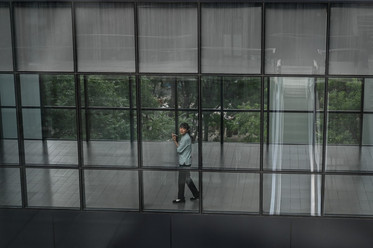 A woman talks on her phone at an office building in Beijing on August 1, 2024. (Photo by JADE GAO / AFP)
