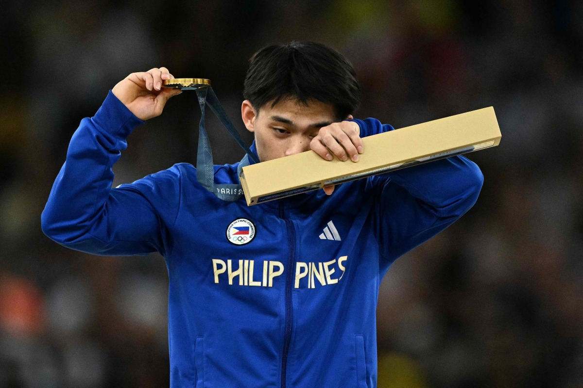 Philippines' Carlos Edriel Yulo celebrates winning the gold medal during the podium ceremony for the artistic gymnastics men's floor exercise during the Paris 2024 Olympic Games at the Bercy Arena in Paris, on August 3, 2024. (Photo by Lionel BONAVENTURE / AFP)
