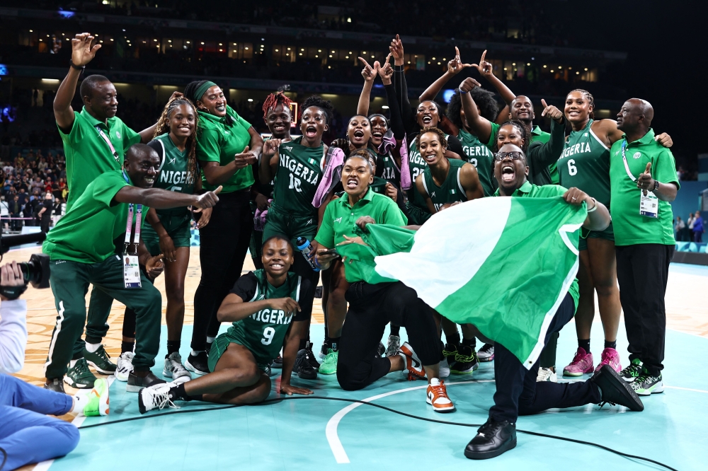 Nigeria's players and staff pose as they celebrate after winning the women's preliminary round group B basketball match between Canada and Nigeria during the Paris 2024 Olympic Games at the Pierre-Mauroy stadium in Villeneuve-d'Ascq, northern France, on August 4, 2024. (Photo by Sameer Al-Doumy / AFP