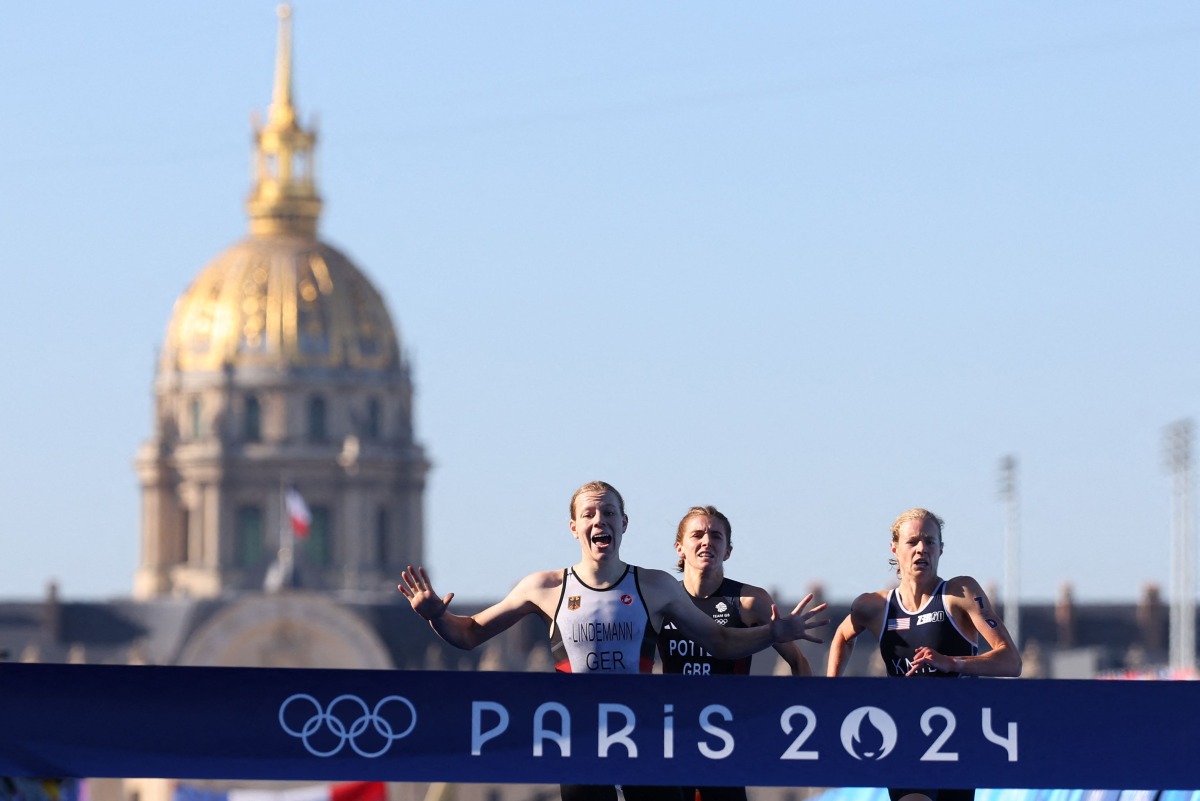 Germany's Laura Lindemann (L) runs to cross the finish in first place followed by Britain's Beth Potter (C) and US' Taylor Knibb, on the Pont Alexandre III at the end of the mixed's relay triathlon race, at the Paris 2024 Olympic Games, in central Paris, on August 5, 2024. (Photo by Franck FIFE / AFP)