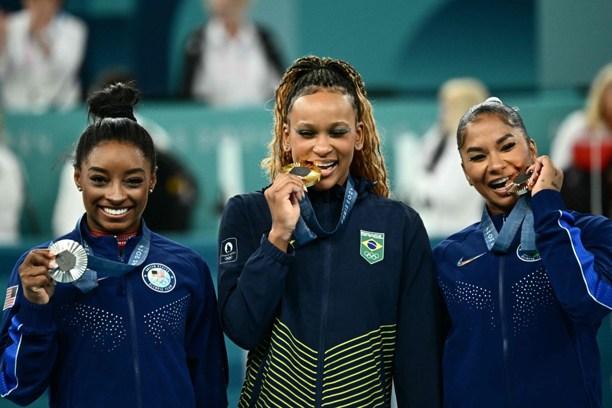 US' Simone Biles (silver), Brazil's Rebeca Andrade (gold) and US' Jordan Chiles (bronze) pose during the podium ceremony for the artistic gymnastics women's floor exercise event of the Paris 2024 Olympic Games at the Bercy Arena in Paris, on August 5, 2024. (Photo by Loic VENANCE / AFP)