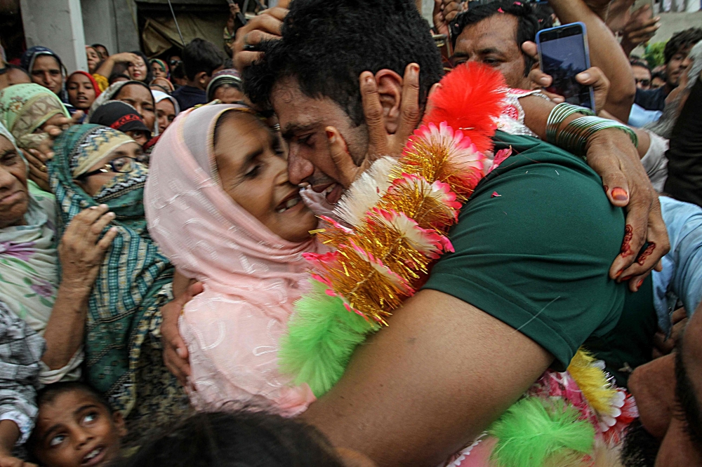 Arshad Nadeem (R), Pakistan's javelin gold medallist at the Paris 2024 Olympic Games, hugs his mother Raziah Parveen upon his arrival at his hometown in Mian Channu on August 11, 2024. (Photo by AFP)
